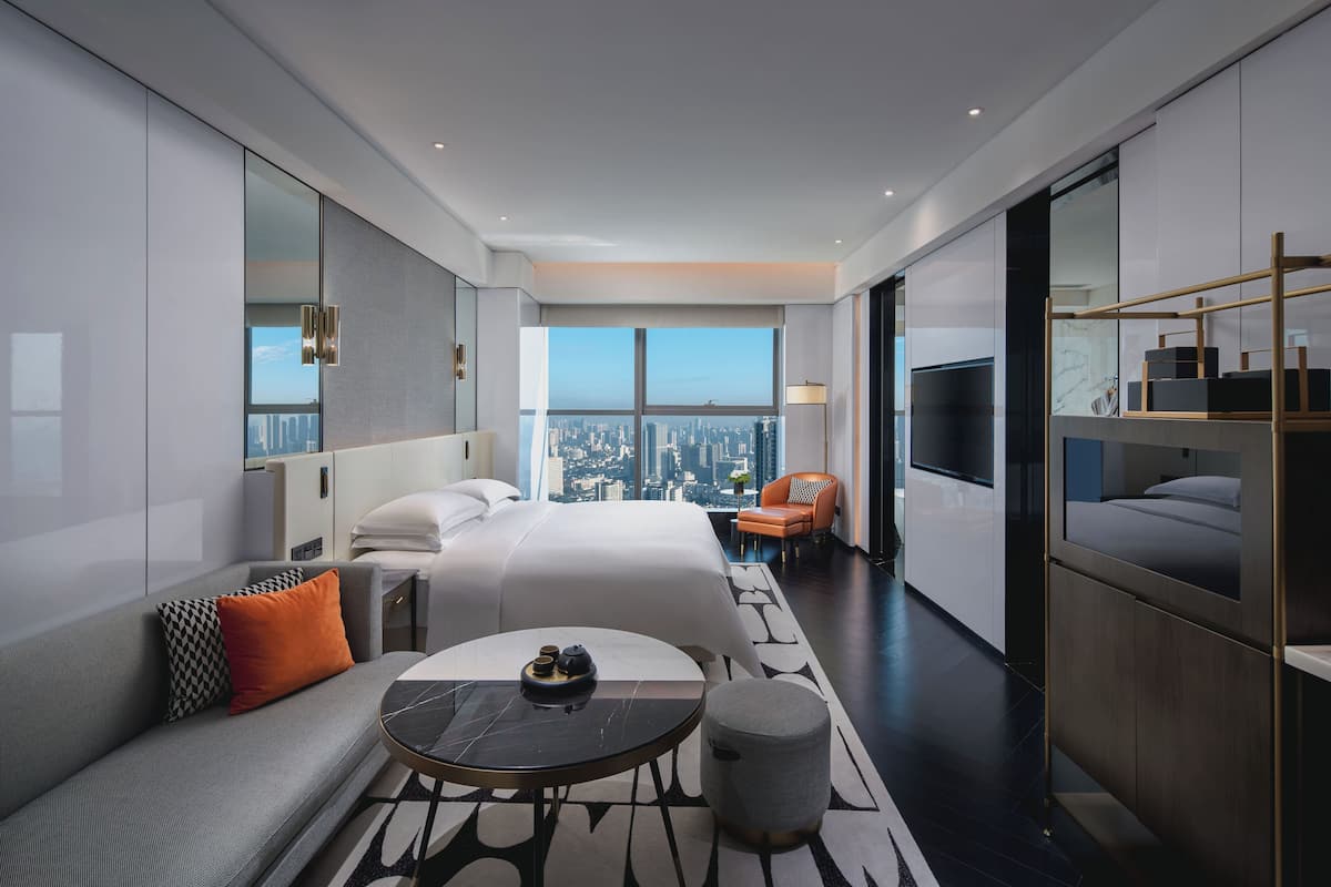 Une chambre d’hôtel moderne avec un grand lit, un canapé, une petite table et un téléviseur.