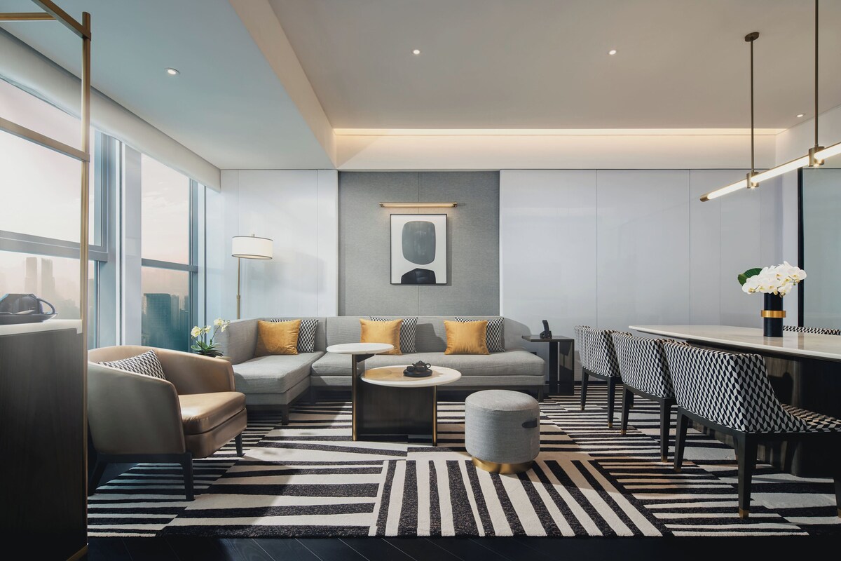 Een moderne woonkamer met een bank, fauteuils, een salontafel en een eethoek met stoelen.