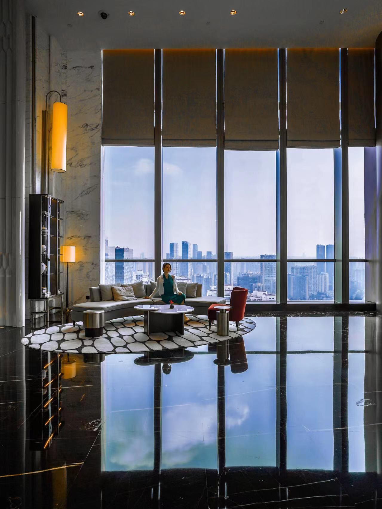 A spacious living area with a city view, a sofa, a coffee table, and a red chair.