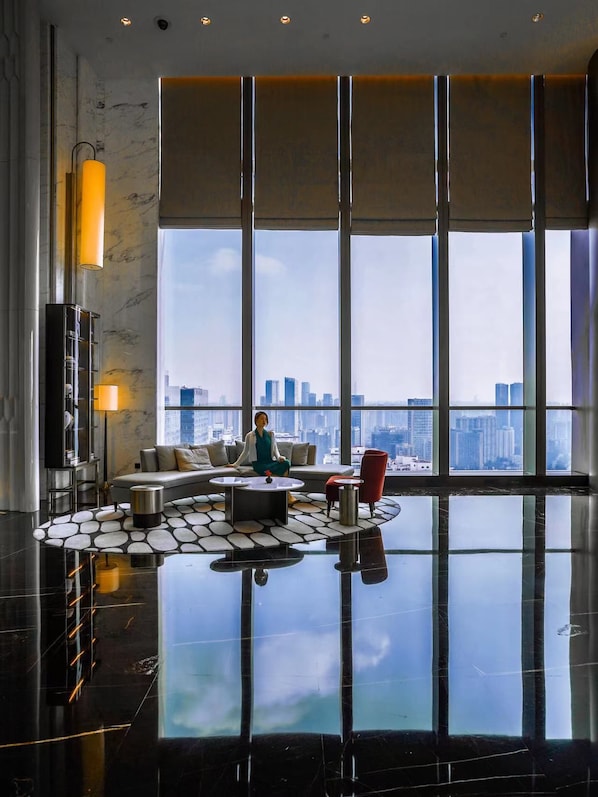 A spacious living area with a city view, a sofa, a coffee table, and a red chair.