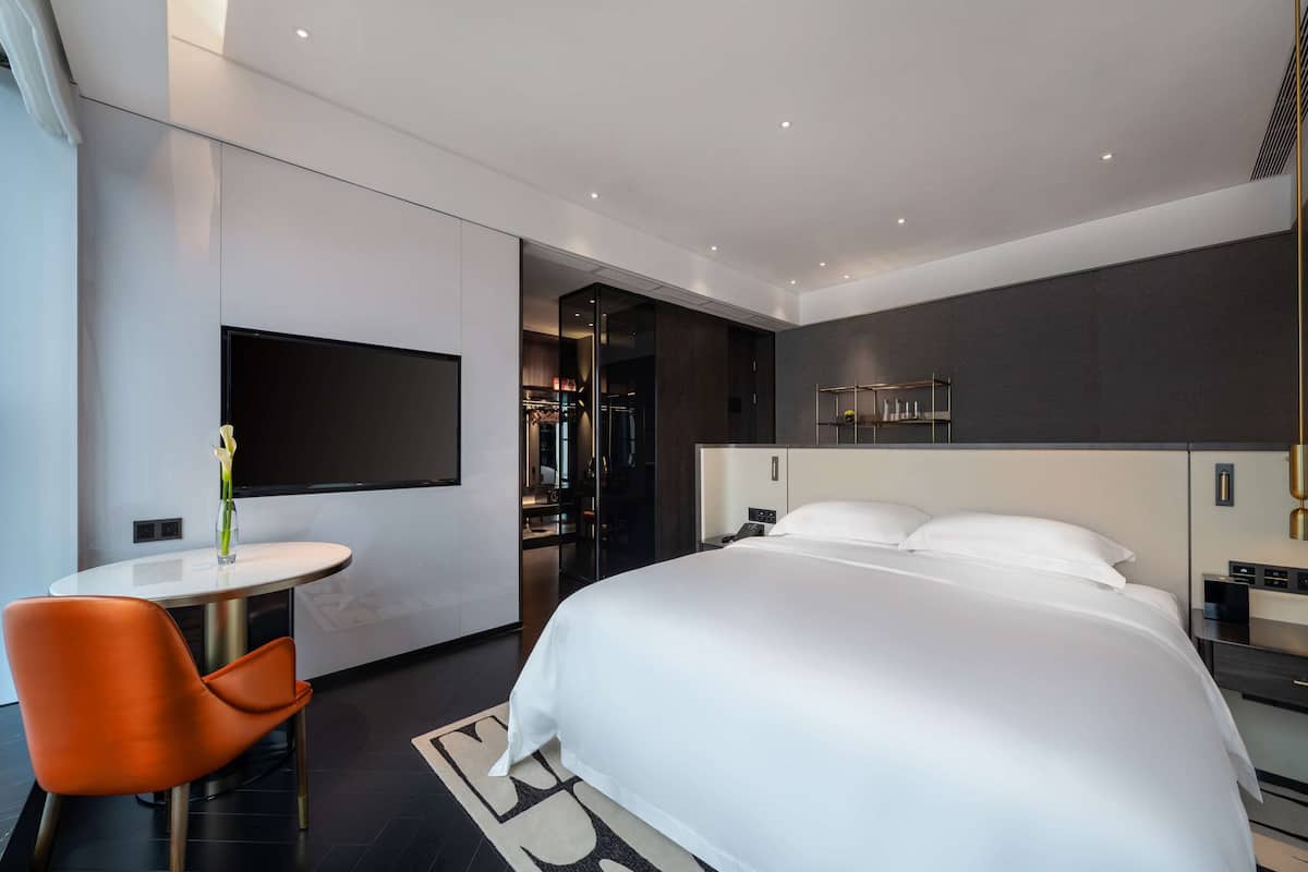 Une chambre d’hôtel moderne avec un grand lit, une petite table ronde et une chaise.