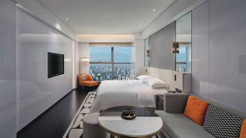 Una habitación de hotel moderna con una cama grande, un sofá, una mesita redonda y vistas a la ciudad.