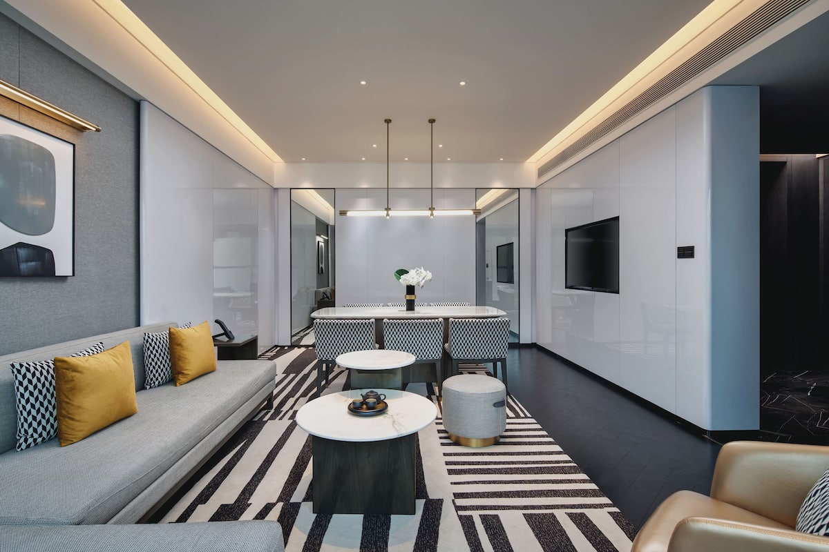 Une chambre d’hôtel moderne équipée d’un canapé, d’une table à manger et d’un téléviseur.
