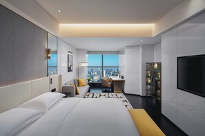 Een moderne hotelkamer met een groot bed, een bureau en uitzicht over de stad.