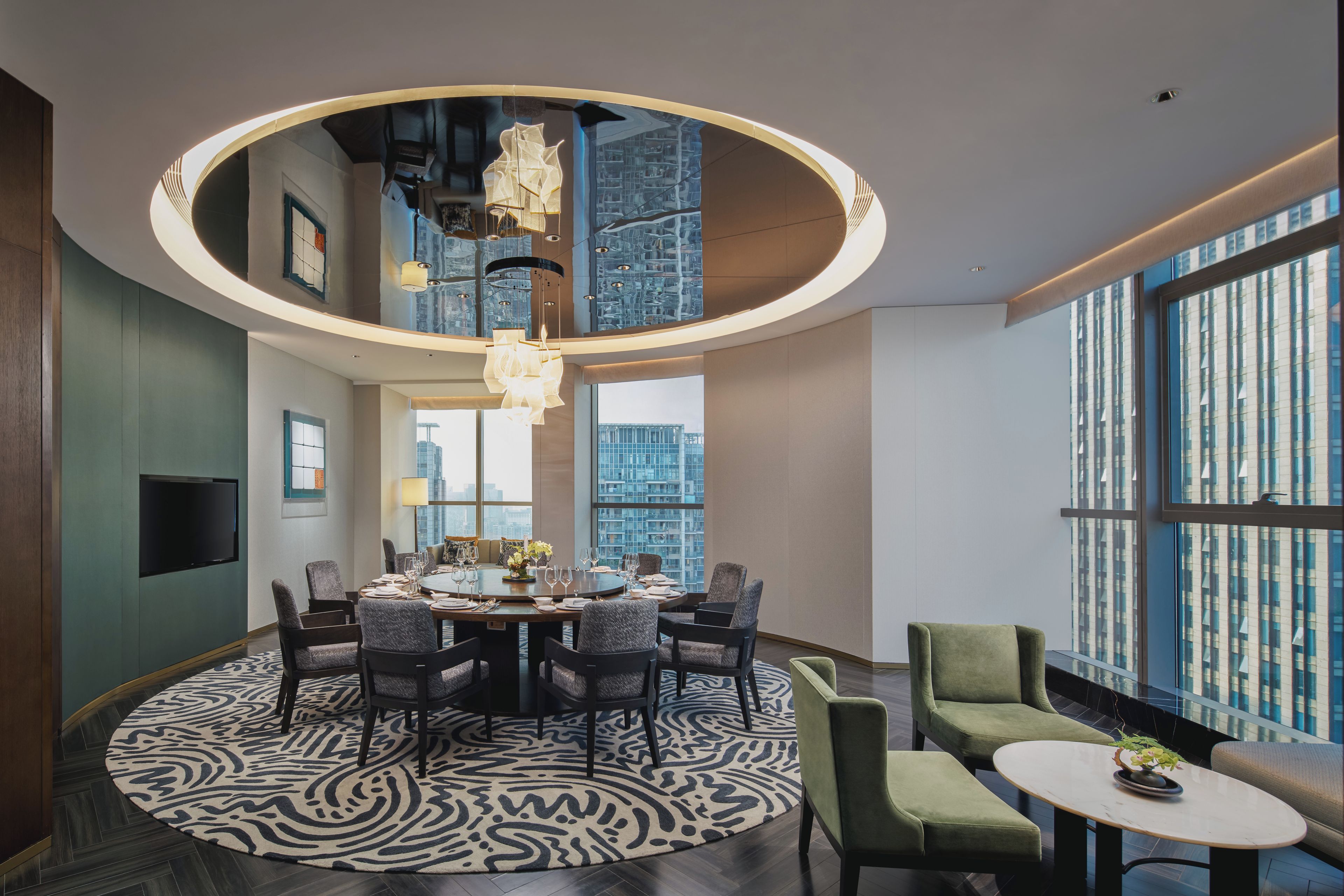 A modern dining area with a round table, chairs, and a patterned rug.