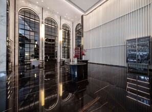 Een moderne lobby met marmeren vloeren, grote gewelfde ramen en een receptiebalie.