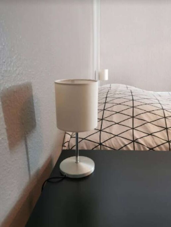 A room with a bed, a bedside table, and a lamp.