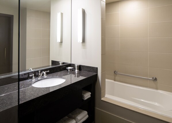 A modern bathroom with a black granite countertop, a white sink, and a bathtub.
