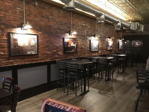 A restaurant with brick walls, hanging pendant lights, and framed pictures. Tables and chairs are arranged for dining. - Experience history in a restored mining town (Shawnee)