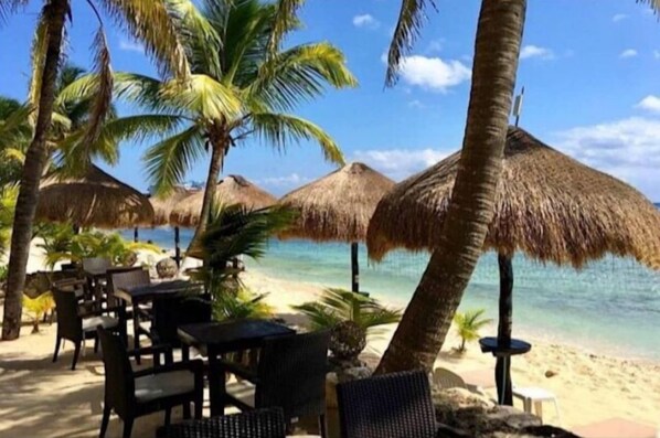 A beachside restaurant with thatched umbrellas and outdoor seating.