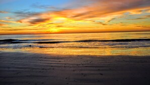 Una playa con un atardecer sobre el océano.