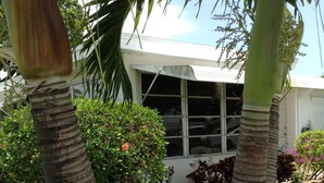 Una casa con facciata bianca, una finestra e un piccolo giardino con erba e qualche pianta.