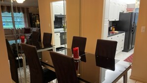 Zona pranzo con tavolo in vetro, quattro sedie e una candela rossa.