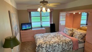 Una camera da letto con un letto, una cassettiera, una TV e una ventola a soffitto.