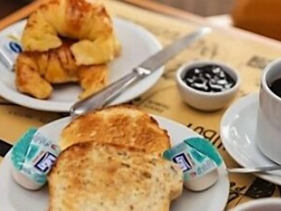 Una mesa con croissants, mantequilla, café y una taza de té.