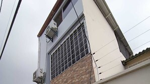 Ein Gebäude mit einer grauen Tür, einem Fenster mit Metallgitter und einer Klimaanlage an der Wand.