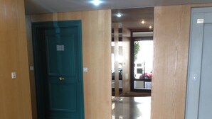 Un pasillo con una puerta verde azulada, paredes de madera y un suelo pulido.