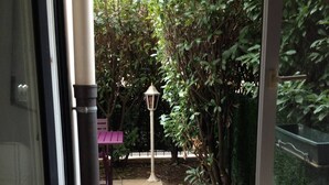Habitación con ventana que da a un jardín, con una mesa y una lámpara.