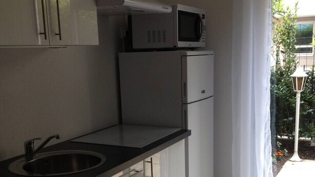 Una cocina moderna con microondas integrado, pileta de acero inoxidable y muebles de cocina blancos.