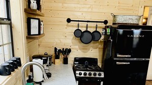 A kitchen with wooden walls, a stove, oven, sink, and hanging pots.