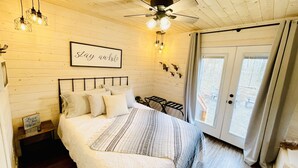 A cozy bedroom with a bed, a ceiling fan, and a sign that says "Stay awhile".