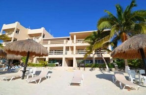 Enjoy stunning ocean views from this beachfront hotel's flat roof, surrounded by lounge chairs and palm trees.