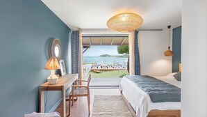 Un dormitorio con cama, escritorio, silla y vista al mar.