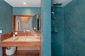 Une salle de bain avec un meuble-lavabo en bois, un grand miroir et une douche.