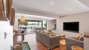 Un amplio salón con un sofá grande, televisión y vistas al exterior.