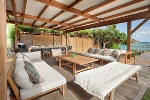 Un espace extérieur abrité, aménagé avec du mobilier en bois, une table et un barbecue.