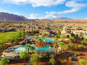 A residential area with multiple houses, a central swimming pool, and a mountainous backdrop. - Sun-kissed in Paradise Village at Zion (Santa Clara)