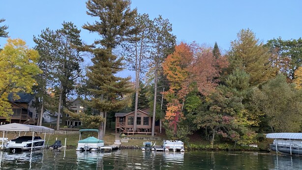 Una cabaña junto al lago con barcos amarrados y un porche cubierto.