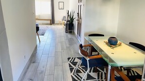 Een moderne eetruimte met een glazen tafel, metalen stoelen en een kamerkleed met een patroon.