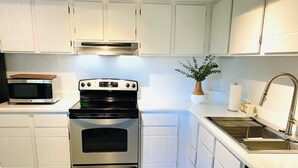 Een moderne keuken met witte kasten, een roestvrijstalen oven, een magnetron en een spoelbak met kraan.