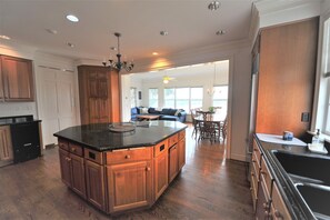 A spacious kitchen with wooden cabinets, a large island, and a dining area with a sofa and table.