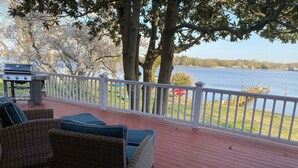 A deck with wicker furniture and a grill, overlooking a lake with a dock and trees. - Beautiful, spacious waterfront home, an easy walk to historic Chestertown (Chestertown)