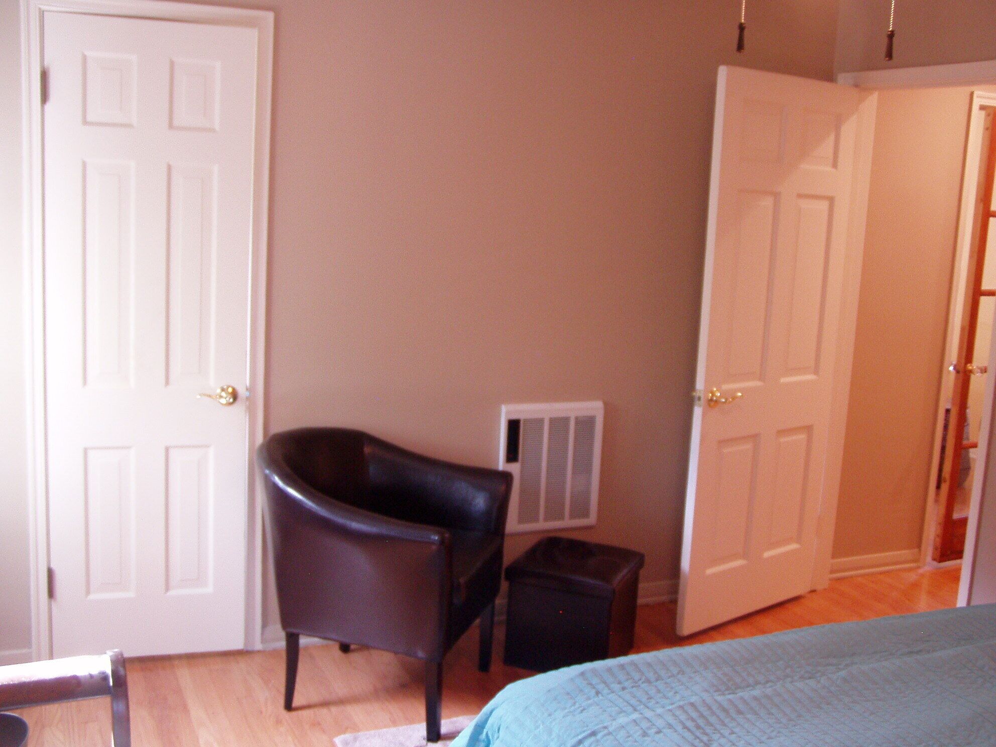 A bedroom with a bed, a chair, a radiator, and two doors.