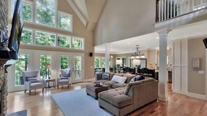 A spacious living room with a sectional sofa, two armchairs, and a coffee table. Large windows provide natural light and a view of the outdoors. - Foreststone Fabulous Lake Keowee Waterfront Home (West Union)