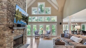 A spacious living room with a stone fireplace, large windows, and a cozy seating area. - Foreststone Fabulous Lake Keowee Waterfront Home (West Union)