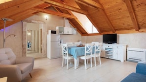 A cozy attic room with a dining table, chairs, a TV, and a kitchenette. - Heritage Family Apartment Mama 3 in Omiš, free parking (Omiš)