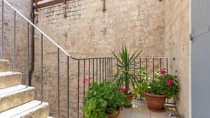 A stone staircase leading to a balcony with potted plants and a metal railing. - Heritage Family Apartment Mama 3 in Omiš, free parking (Omiš)