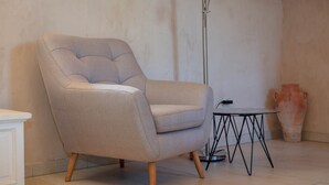 A beige armchair with wooden legs, a small round table with a black metal frame, and a tall floor lamp. - Heritage Family Apartment Mama 3 in Omiš, free parking (Omiš)