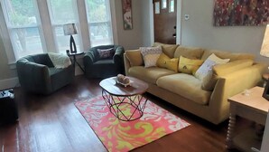 Una sala de estar con ventilador de techo, un sofá, una mesa de centro y una alfombra.