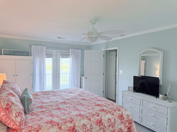 A bedroom with a bed, a ceiling fan, a dresser, a mirror, and a window with curtains. - THE MARSH MELLOW- Beautiful Marsh Front home / 4 minute walk to beach (Murrells Inlet)