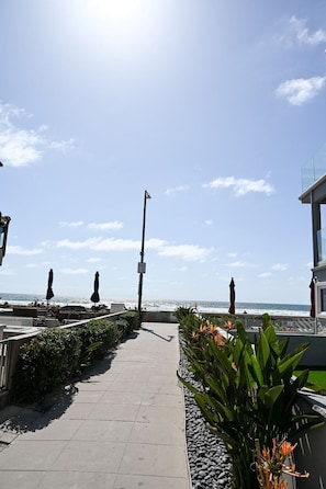 Stroll along the oceanfront promenade, lined with lush greenery and shaded by umbrellas.