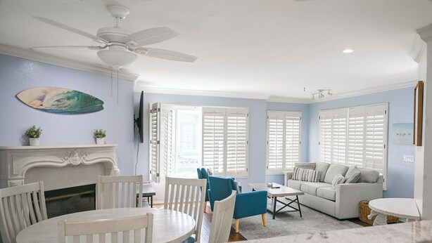 A living room with a fireplace, a ceiling fan, and a sofa.
