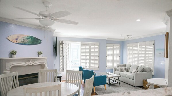 A living room with a fireplace, a ceiling fan, and a sofa.