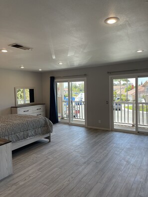 A spacious bedroom with a large bed, a dresser, and a sliding glass door leading to a balcony. - Rare to find house of 5 BR and 4 Bath with big backyard in Fountain Valley.  (Fountain Valley)