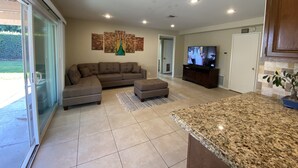 A spacious living room with a sectional sofa, a television, and a kitchen area with granite countertops. - Rare to find house of 5 BR and 4 Bath with big backyard in Fountain Valley.  (Fountain Valley)
