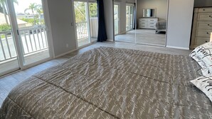 A bedroom with a large bed, a dresser, and a mirror. There are sliding glass doors leading to a balcony. - Rare to find house of 5 BR and 4 Bath with big backyard in Fountain Valley.  (Fountain Valley)